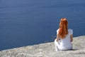 Red-haired girl looking over blue water