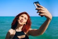 Red-haired woman takes selfie on smartphone camera. Royalty Free Stock Photo