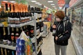 Red-haired girl in a medical mask buys wine in a supermarket.