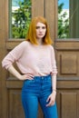 Red-haired girl near wooden doors Royalty Free Stock Photo