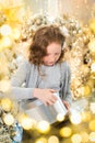 Red-haired girl opens a gift near the Christmas tree. smiles, garland, lights, festive, new year Royalty Free Stock Photo