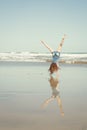 Red haired girl doing a hand stand or cartwheel on a New Zealand surf beach Royalty Free Stock Photo