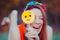 Red haired girl playing with yellow emoji candy on a stick Royalty Free Stock Photo