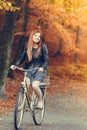 Red haired girl riding on bike in autumnal park Royalty Free Stock Photo