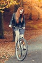 Red haired girl riding on bike in autumnal park Royalty Free Stock Photo