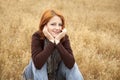 Red-haired girl sitting at yellow autumn grass. Royalty Free Stock Photo