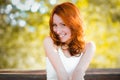 The red-haired girl smiles sweetly, laughs back. real emotions. A pretty woman with naturally curly red hair and a happy, vibrant Royalty Free Stock Photo