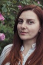 Red haired girl smiling at the camera in the botanical garden Royalty Free Stock Photo