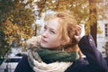 A red-haired girl standing in the middle of the city Park in the autumn