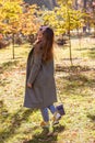 Red haired girl in sunglasses and a coat walks in an autumn park on a sunny day Royalty Free Stock Photo