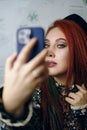 Red-haired girl takes a selfie on the front camera of a modern smartphone. Royalty Free Stock Photo