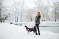 Red haired girl walking at park with husky dog on winter day. Royalty Free Stock Photo