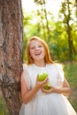 Red-haired girl in a white dress with a green apple in her hands Royalty Free Stock Photo