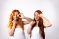 Red-haired girlfriends wrapped in a white towels with cucumber slices for a facial mask. White background Royalty Free Stock Photo