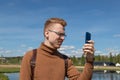 red-haired man with glasses takes a selfie on his phone