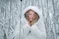 Red-haired mature woman with hooded coat stands smiling contentedly in the winter cold in the snowy reeds