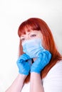 Red-haired middle-aged woman is putting on a disposable mask on white Royalty Free Stock Photo
