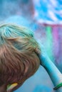 Red haired person holds blue paint covered hand to their head after completing a Colour Paint Run in aid of charity