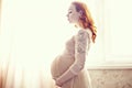 Red-haired pregnant woman in a delicate pink lace dress Royalty Free Stock Photo
