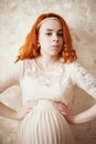 Red-haired pregnant woman in a delicate pink lace dress Royalty Free Stock Photo