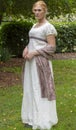 Regency woman in cream dress walks alone in a summer garden