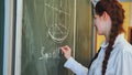 A red-haired schoolgirl draws geometric shapes on the board. Royalty Free Stock Photo