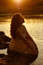 The red-haired sensual girl in white dress sitting on the rocks Royalty Free Stock Photo