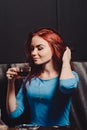 Red-haired girl in a cafe smoking a hookah dressed in a blue blouse