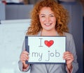 Red haired smiling businesswoman holding small poster. Royalty Free Stock Photo
