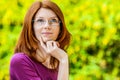 Red-haired smiling young woman with glasses reflects