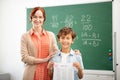 Red-haired teacher smiling and hugging her clever pupil