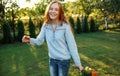 a red-haired teenage girl is dancing on the lawn with a bouquet of flowers in her hand. sunny sunset Royalty Free Stock Photo