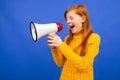 Red-haired teenage girl shouting into the microphone the news on a blue studio background Royalty Free Stock Photo