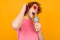 Red-haired teenager singer in headphones sings on a yellow background