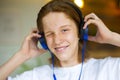 Red-haired teenager wearing blue headphones. He listens to music and smiles. Royalty Free Stock Photo