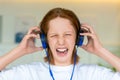 Red-haired teenager wearing blue headphones. He listens to terrible music and he doesn't like it. Royalty Free Stock Photo