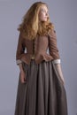 18th century woman in brown outfit on plain studio backdrop Royalty Free Stock Photo