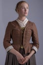 18th century woman in brown outfit on plain studio backdrop Royalty Free Stock Photo