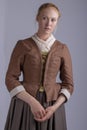 18th century woman in brown outfit on plain studio backdrop Royalty Free Stock Photo