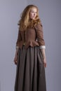 18th century woman in brown outfit on plain studio backdrop Royalty Free Stock Photo