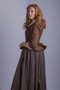 18th century woman in brown outfit on plain studio backdrop Royalty Free Stock Photo