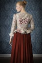 Red-haired 18th century woman standing in front of baroque wall paper Royalty Free Stock Photo