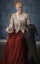 Red-haired 18th century woman standing in front of baroque wall paper Royalty Free Stock Photo