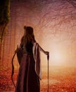 A red-haired woman archer of the Middle Ages with a bow in an autumn forest. Fantasy world Royalty Free Stock Photo