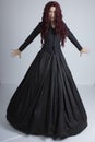 Red-haired woman in Black Victorian ensemble and a witch-like pose