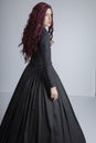 Red-haired woman in Black Victorian ensemble and a witch-like pose Royalty Free Stock Photo