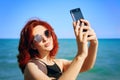 Red-haired woman takes selfie on smartphone camera. Royalty Free Stock Photo