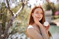 red-haired woman enjoys life in spring blooming garden applying facial cream Royalty Free Stock Photo