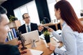 Red-haired woman gives money to lawyer for divorce, sitting at office table.