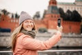 Red-haired woman in glasses traveler in a hat and jacket chatting on a smartphone taking a selfie in Moscow